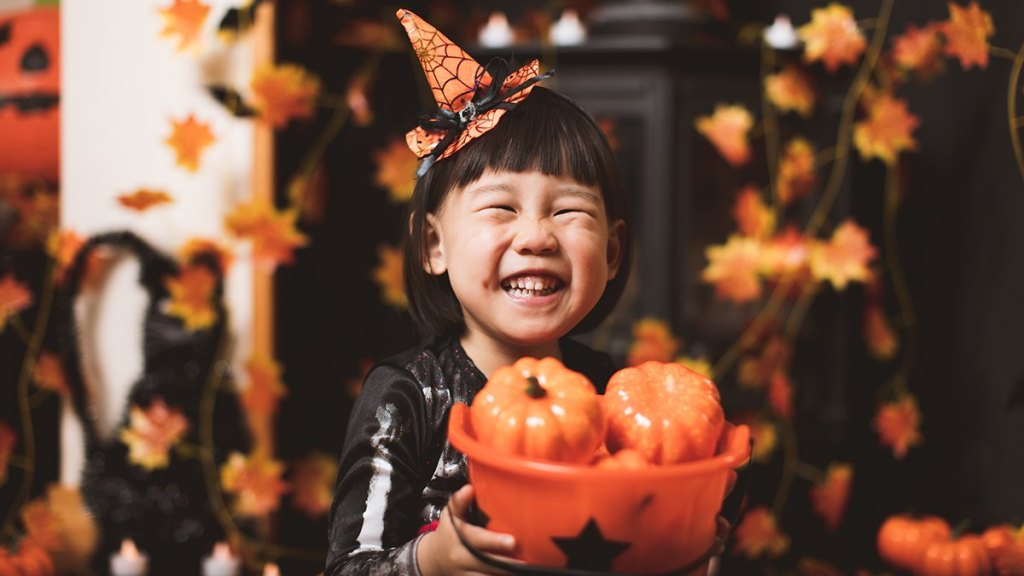 Happy little girl (trick or treater) with basket full of plastic pumpkins